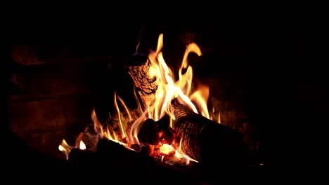 Cálida-Y-Acogedora-Chimenea-De-Madera,-Que-Brilla-Con-Relajantes-Llamas-Anaranjadas-Por-La-Noche,-Serena-Tranquilidad-Al-Aire-Libre