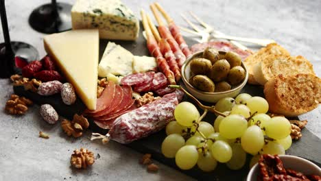 Cold-snacks-board-with-meats--grapes--wine--various-kinds-of-cheese