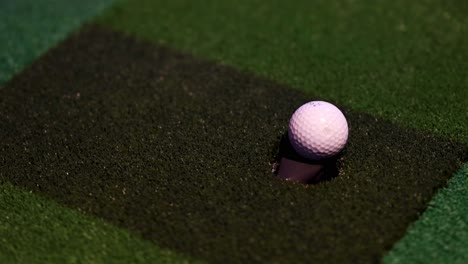 a golf ball moving closer to the cup on green.