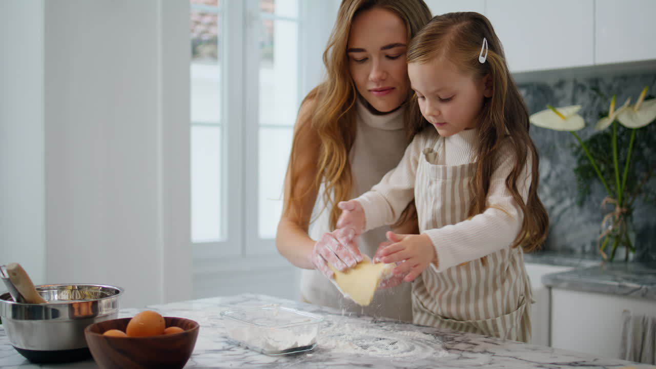 Curious kid sprinkling flour on table closeup. Single mother teach daughter bake