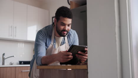 hombre mirando una receta en una tableta en su cocina