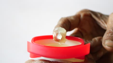 Senior-woman-using-petroleum-jelly-onto-skin-at-home-close-up