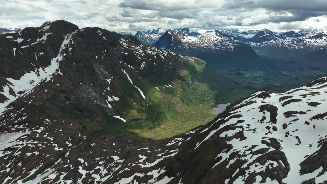 vista aérea panorámica de las montañas cubiertas de nieve y los verdes valles de noruega