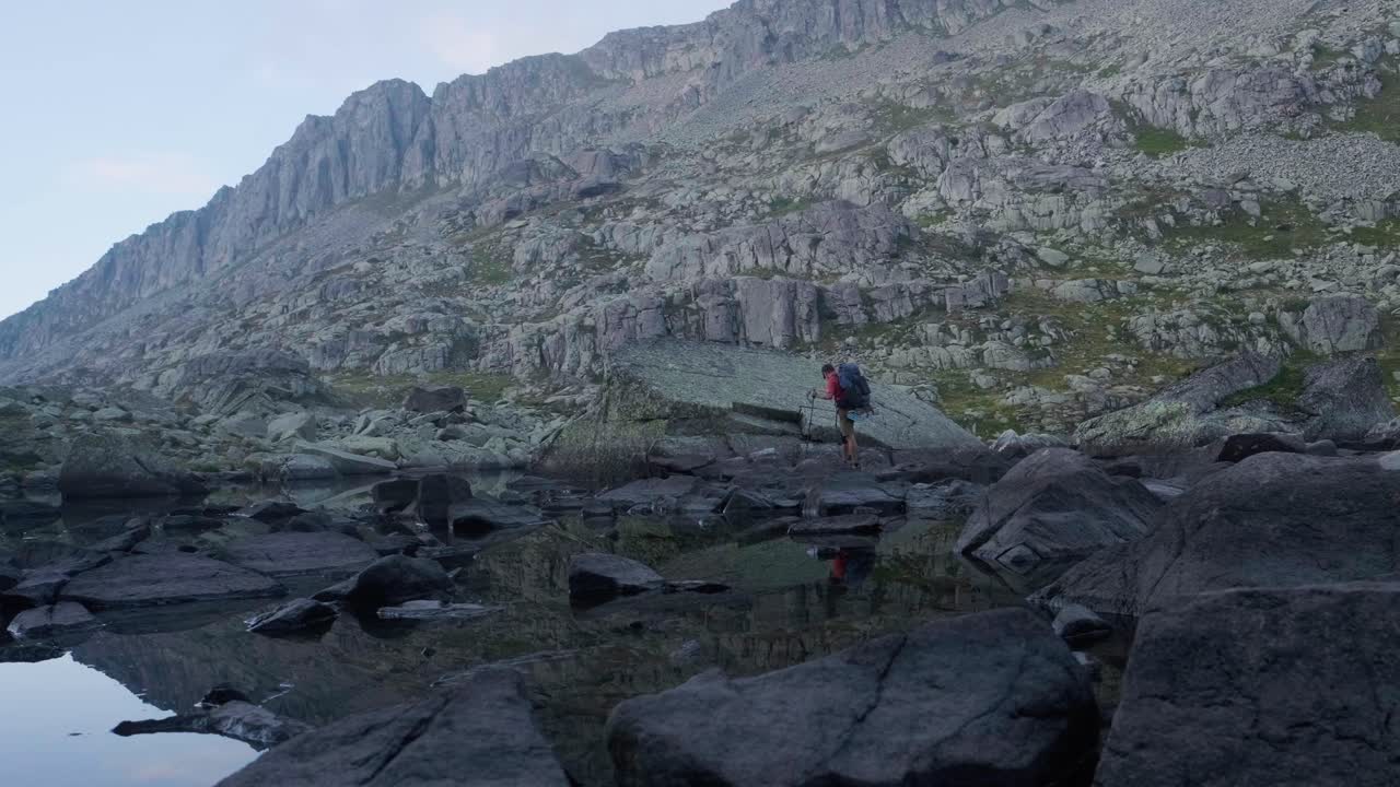 hermosa toma panorámica del lago laghetti di lagorai y un solo excursionista caminando por un sendero rocoso en las montañas