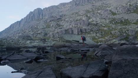 Beautiful-wide-shot-of-lake-Laghetti-di-Lagorai-and-single-hiker-hiking-on-rocky-trail-in-the-mountains