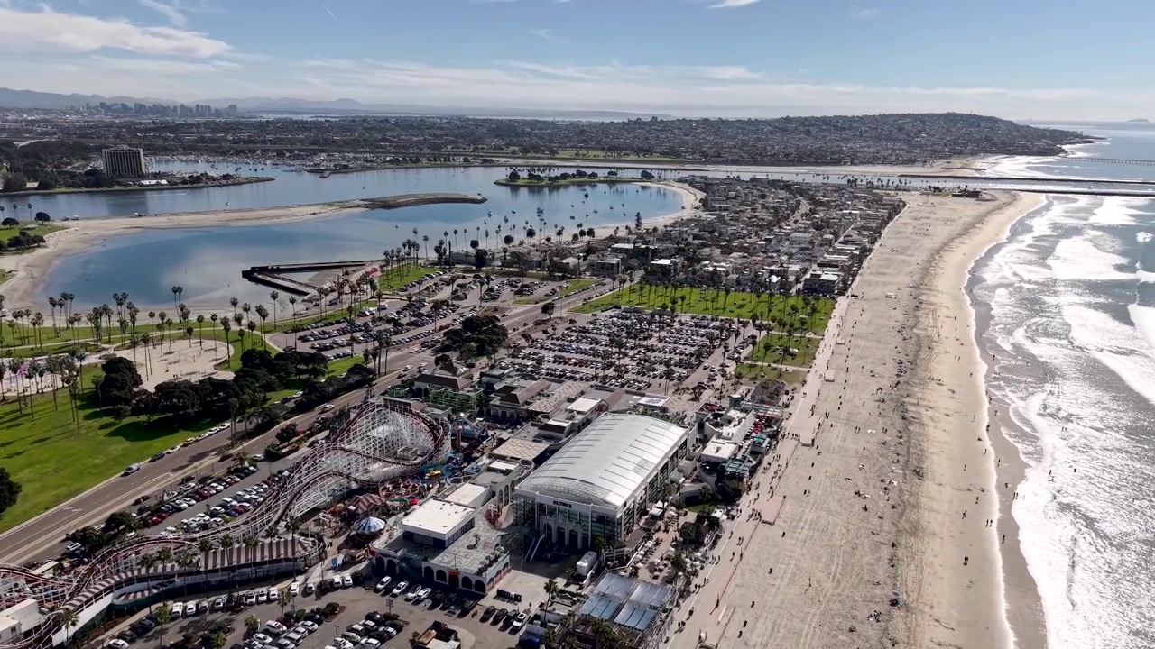 Parque Mission Bay y la montaña rusa de madera de Belmont Park desde arriba, espacio verde de parque junto a la histórica atracción de feria con las aguas de la bahía al fondo, San Diego, California. Atracciones de Parques Temáticos.