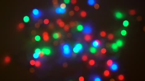 luces borrosas multicolores brillantes de la guirnalda parpadean en el fondo oscuro. preparación de la fiesta. iluminación festiva. primer plano. 4k.