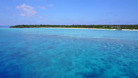 aerial flying over clear deep water to shallow coral reef in the tropics 4k