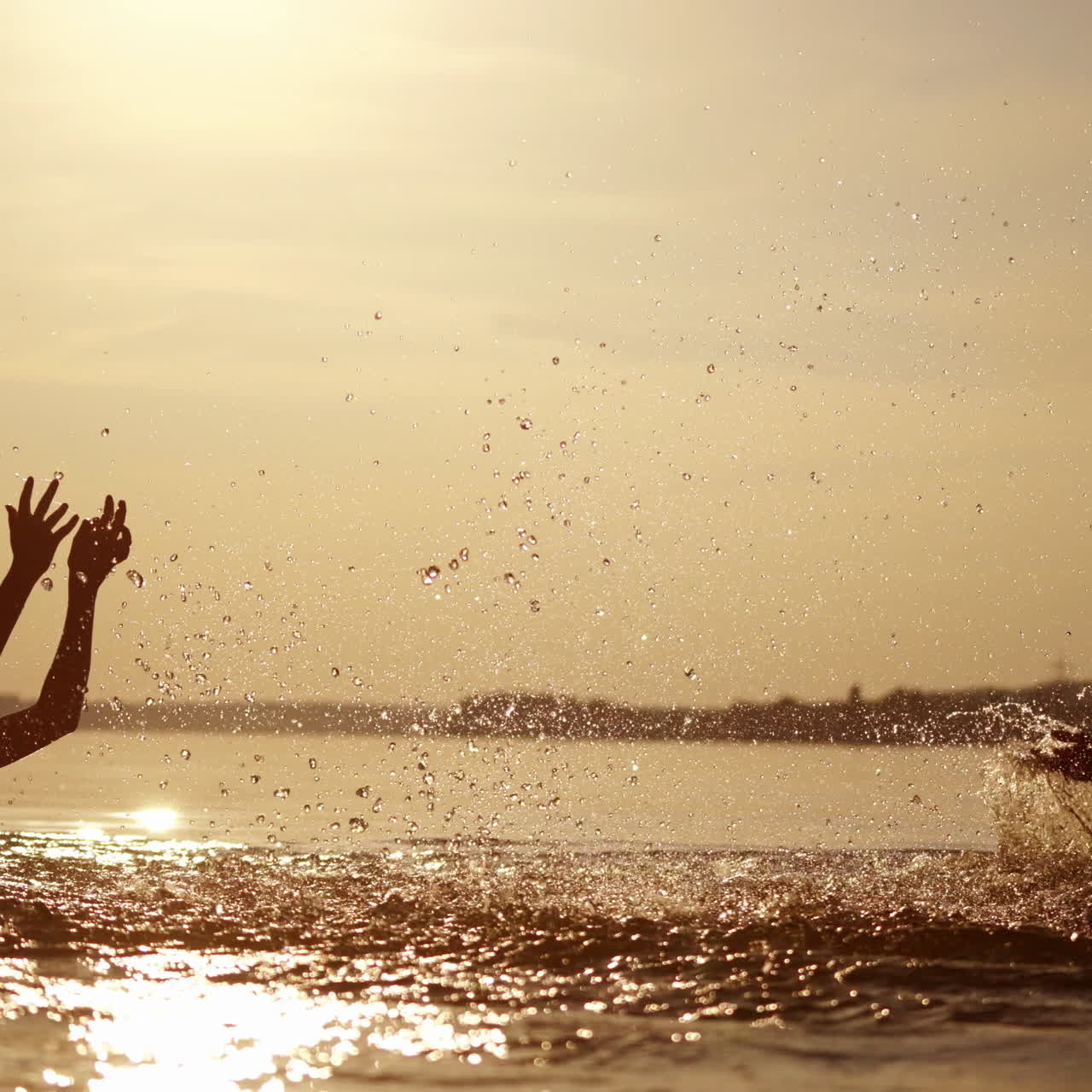 Silhouette of a woman and two boys making splashes in water at sunset. Beautiful evening background in the river and happy family enjoys summer vacation.