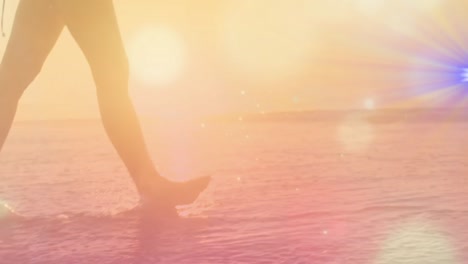 animation of light trails and spots over caucasian woman walking at beach