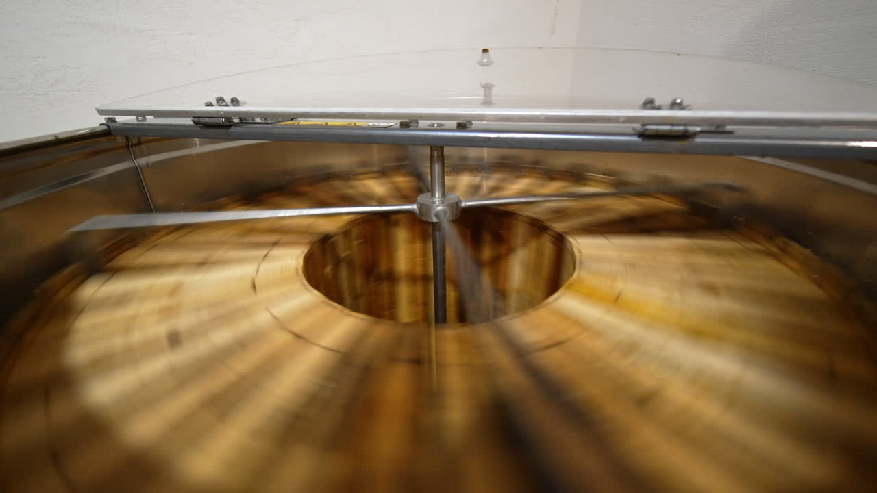 Organic honey production at bee farm. Apparatus spins the wooden frames to extract fresh healthy product from honeycombs.