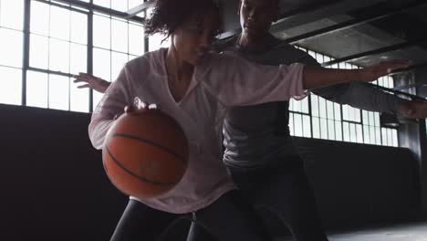 african american man and woman standing in an empty building playing basketball