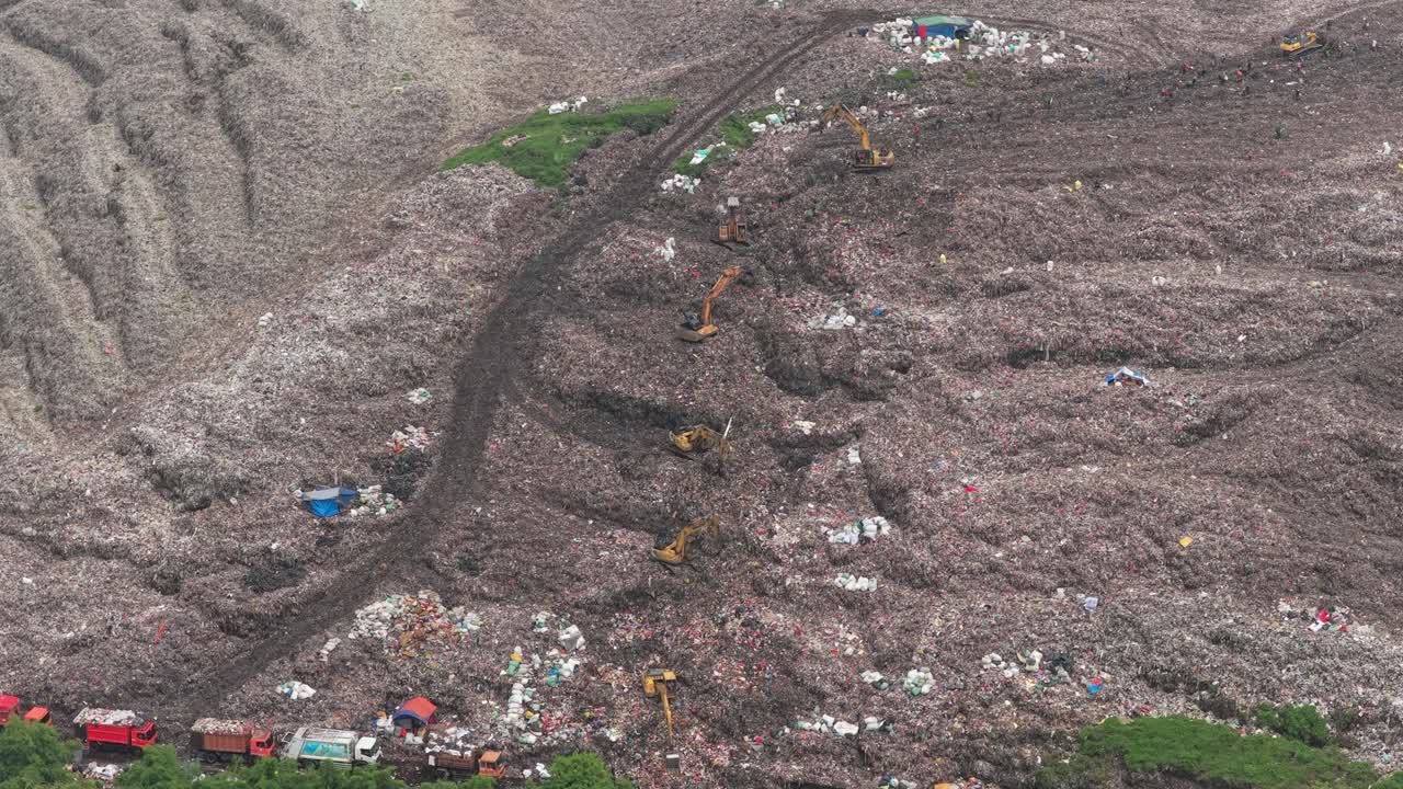 Aerial view of huge landfill with trucks and excavators in jakarta