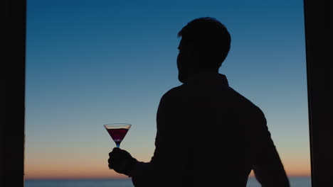 Reisemann,-Der-Im-Urlaub-Alkohol-Trinkt-Und-Den-Wunderschönen-Sonnenuntergang-Beobachtet-Und-Einen-Martini-Cocktail-Genießt.-Tourist,-Der-Sich-Im-Ferienort-Entspannt