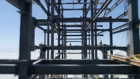 workers are assembling steel structures at a coastal construction site under clear skies. heavy machinery aids in lifting and securing components for the project.