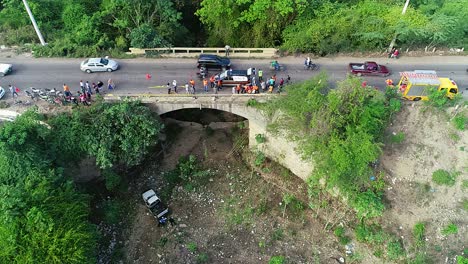 Aerial-view-of-a-rescue-team-searching-for-survivors,-in-a-bridge-car-crash-accident,-queue-of-traffic-passing-by,-in-Mexico,-Central-America---Static,-drone-shot