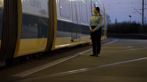 woman in uniform standing next to a train at dusk