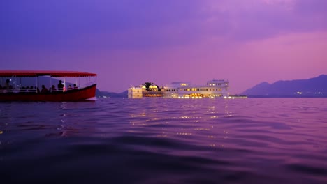el palacio del lago de udaipur jag niwas en la isla en el lago de pichola con barco turístico. puesta de sol en udaipur, india
