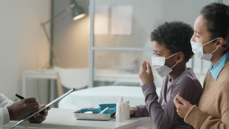 Little-African-American-Boy-and-His-Mother-in-Masks-Talking-with-Pediatrician