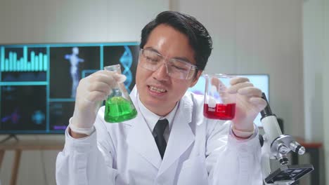 young asian male research scientist holding glass test tube and speaking to the camera