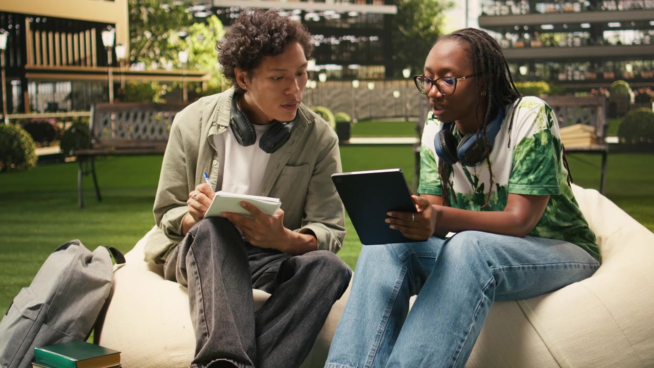 Classmates talking beside laptop on campus for student collaboration