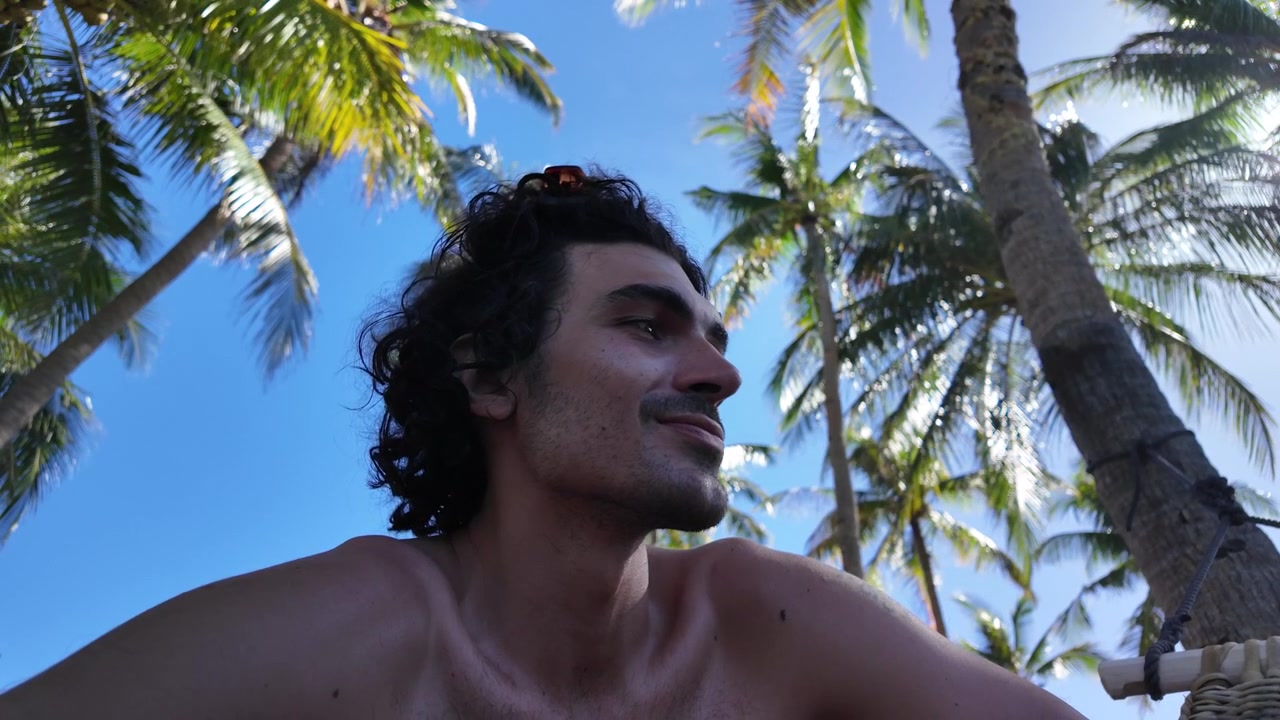 Joven relajándose bajo palmeras tropicales durante un día soleado en la isla