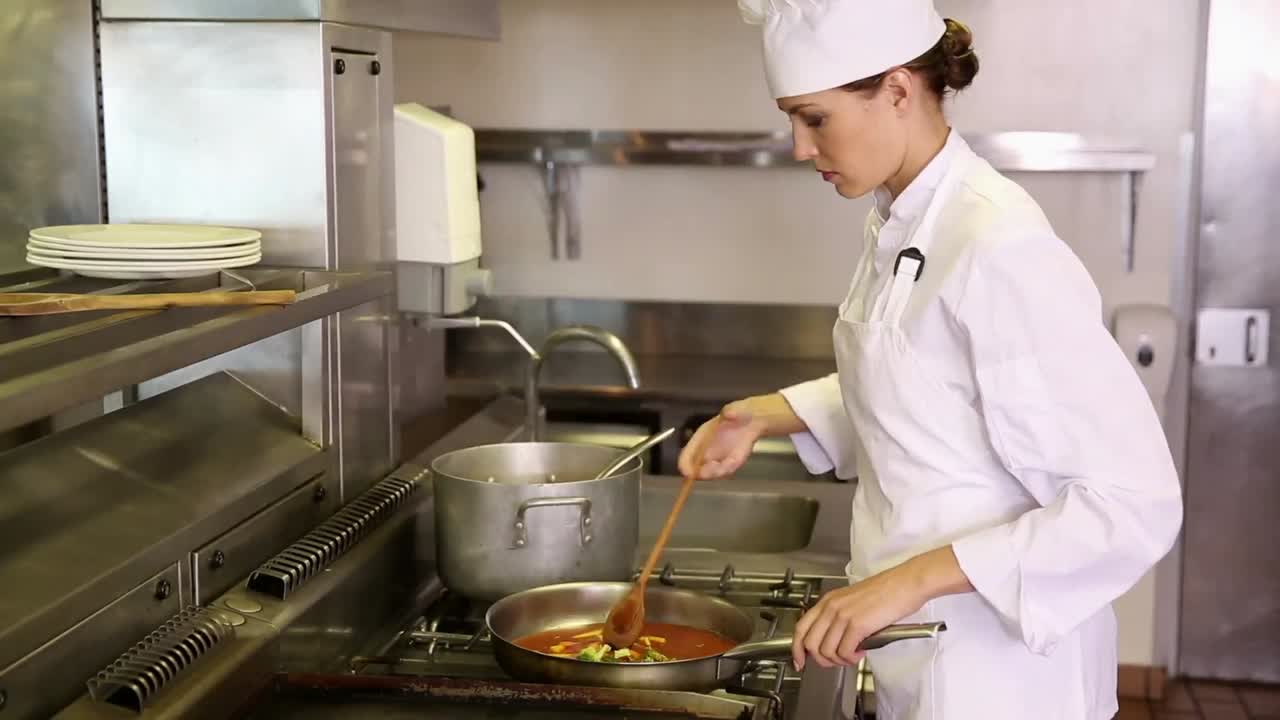 Bella chef che prepara verdure in padella.