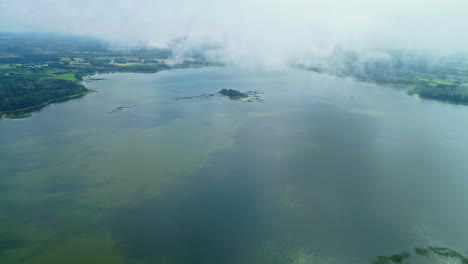 misty landscape with small island on the lake - aerial drone shot