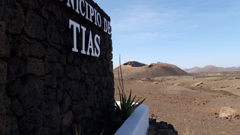 Lanzarote-Landschaft,-Schild-Tias-Im-Vordergrund,-Vulkanberge-Im-Hintergrund