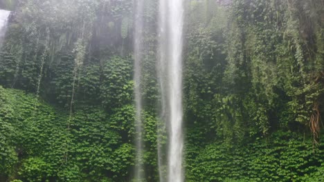 aerial of waterfall in a green jungle with spray covering camera lens causing reflections