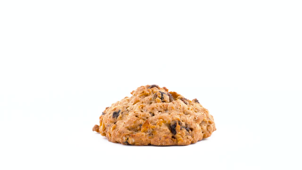 One oatmeal raisin cookie rotating on the turntable. Isolated on the white color background. Close-up. Macro.