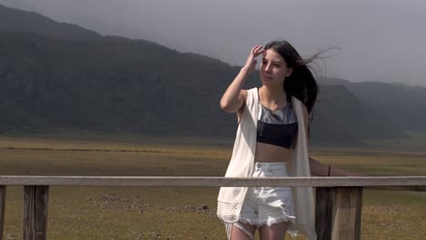 girl in black crop top and white cardigan adjusts hair blowing in wind at cotopaxi national park