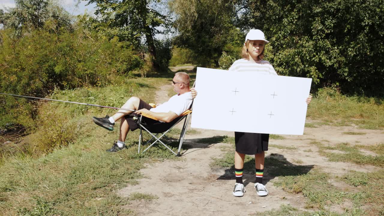 девушка и мужчина ловят рыбу у реки.