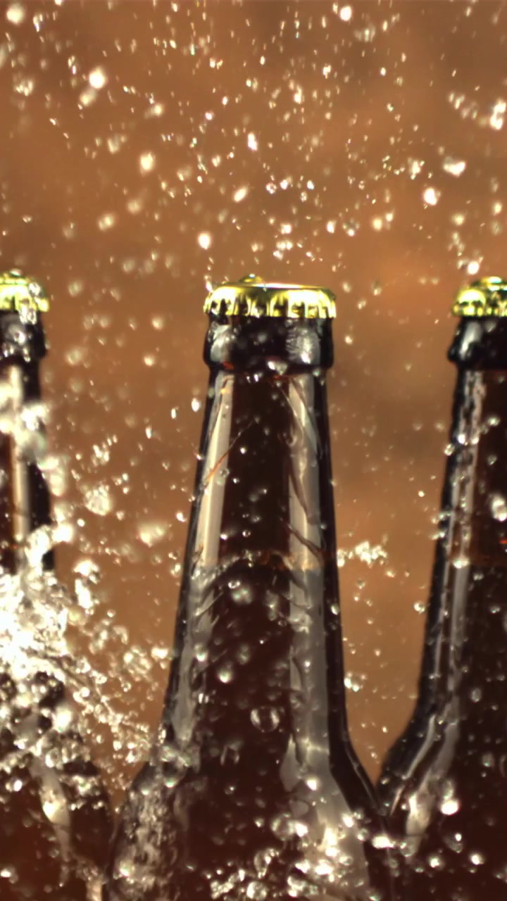 Cámara lenta de agua salpicando sobre tres botellas de cerveza