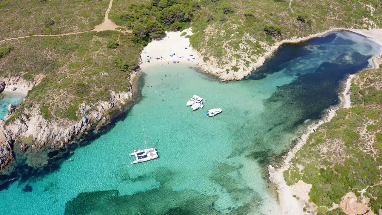 Aerial drone shot over several sailing yachts anchored in the shallow waters below