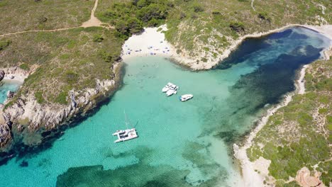 Aerial-drone-shot-over-several-sailing-yachts-anchored-in-the-shallow-waters-below