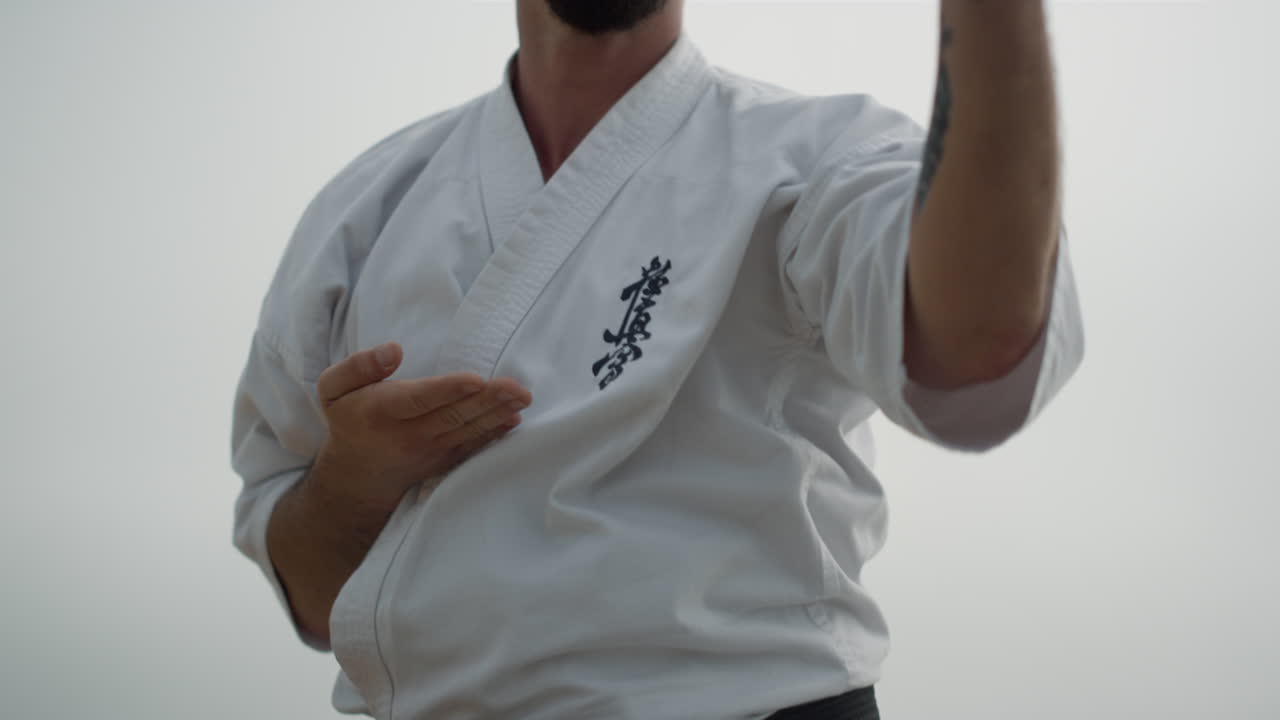 un hombre deportivo practicando karate en la playa de cerca. un luchador entrenando arte material.