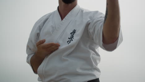 sporty man exercising karate on beach close up. fighter training matrial art.