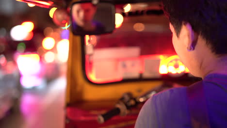 4k footage of tuk tuk driver in bangkok, thailand driving through a busy street