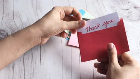 hands holding a red envelope with a thank you note