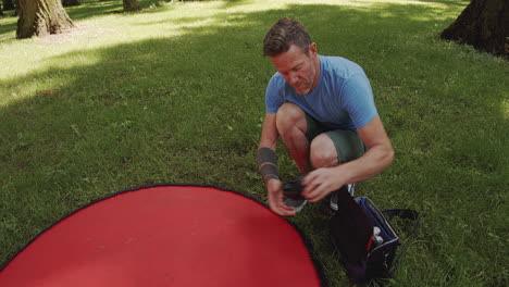 Man-prepares-small-drone-ready-for-flight-in-park,-sunny-day,-close-up