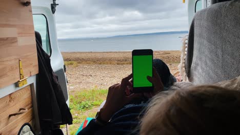 young woman use smartphone viewing green screen in camping car on mobile phone browsing chroma key