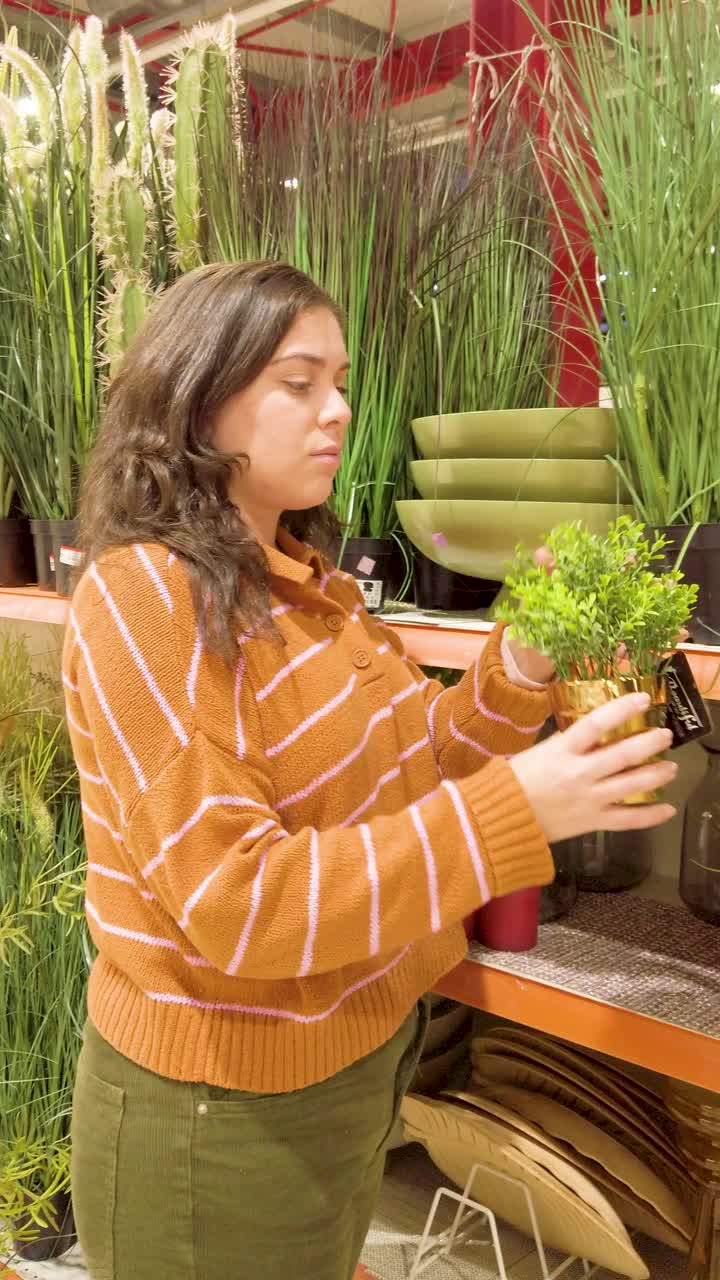 Young woman buying a small decorative plant in a store.
