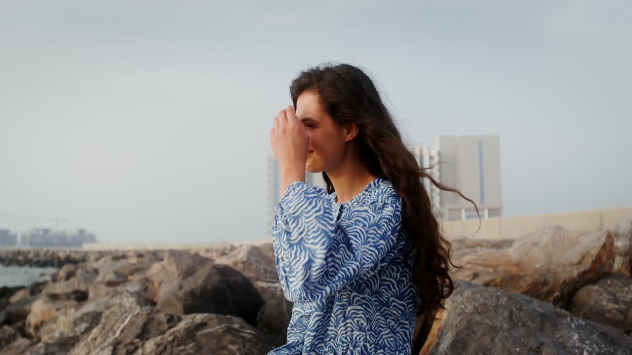 mujer sentada en las rocas junto al mar