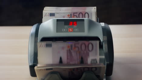 euro bills counting machine close up. man hand putting currency into equipment.