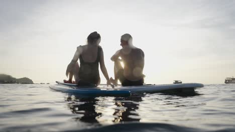 couple paddleboarding on the water at sunset