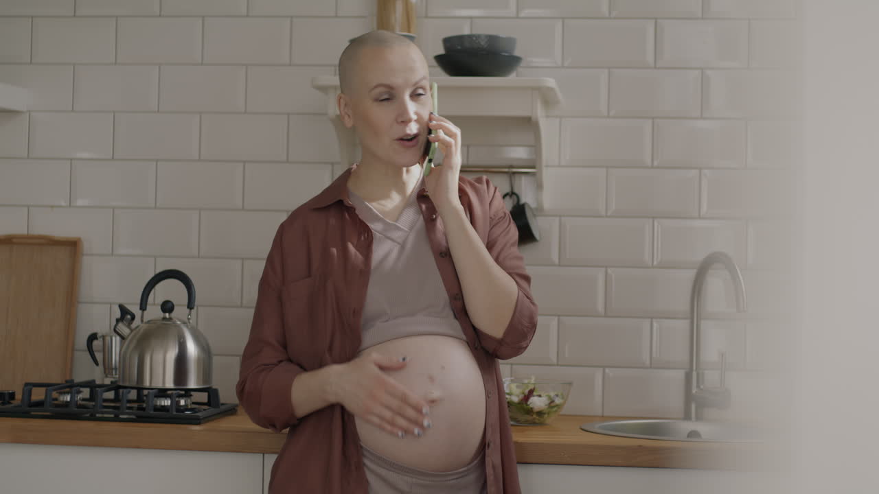 Pregnant Woman Talking on Phone in the Kitchen