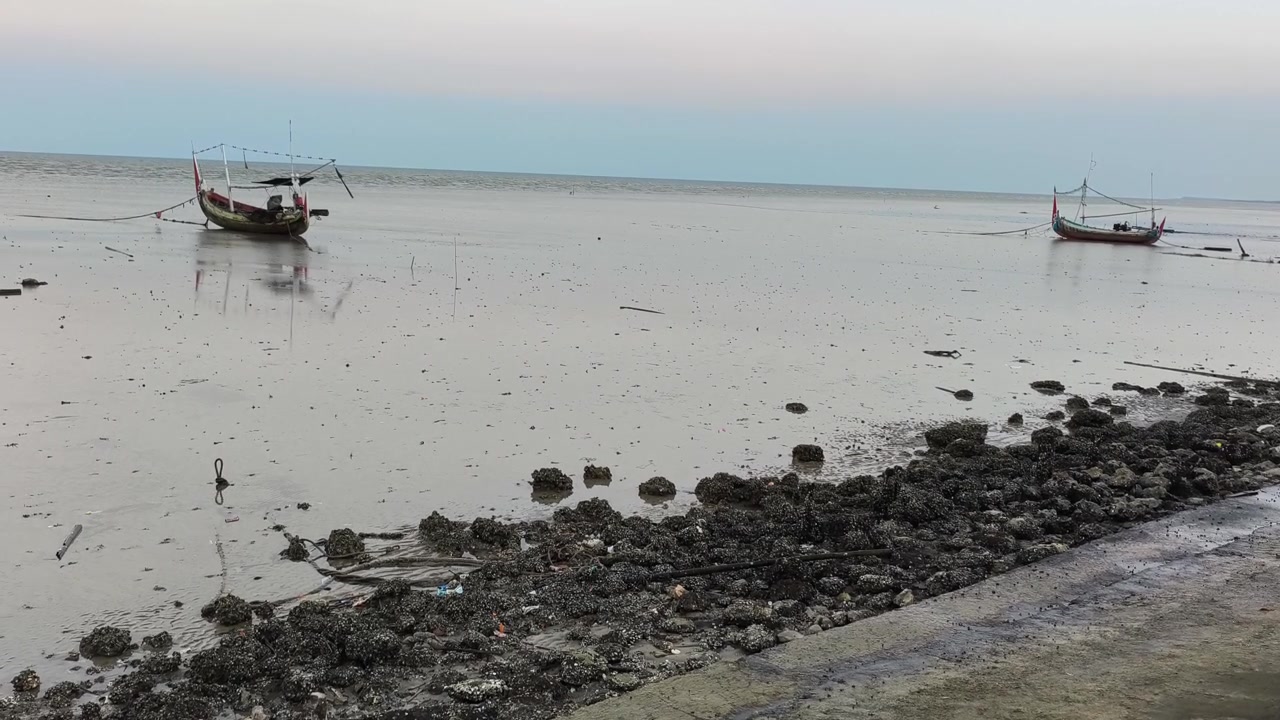 Tradiční rybářské lodě zakotvené na bahnitém pobřeží při odlivu