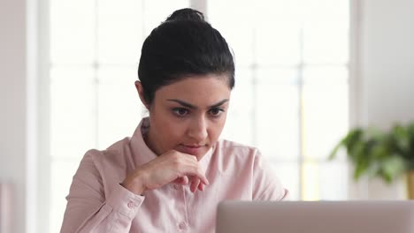 mujer de negocios india enfocada usando una computadora portátil pensando haciendo investigación en la oficina