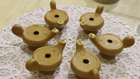 six isolated gold candle holders shaped as oil lamps sitting on a table, rotating shot during a communion